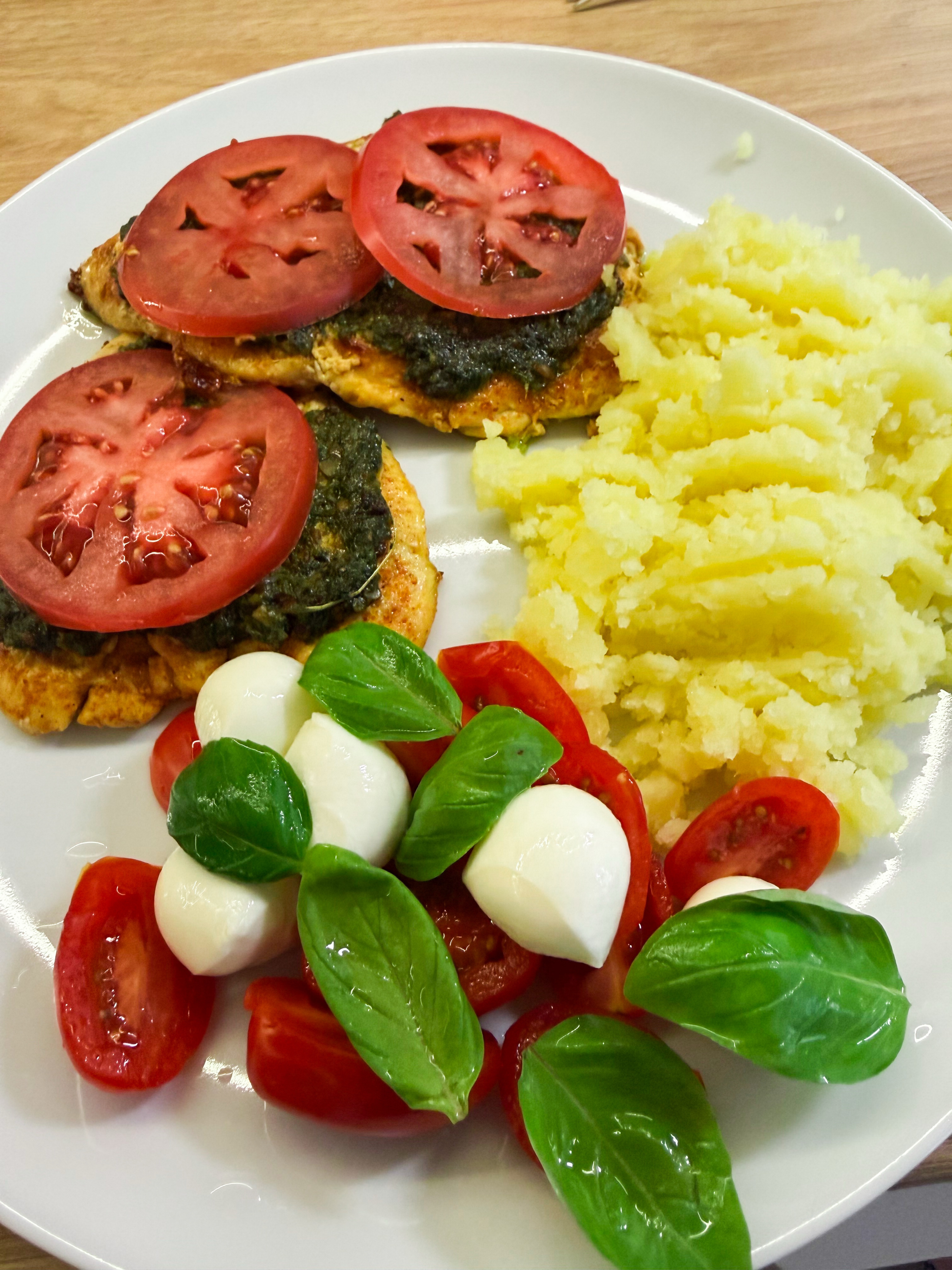 Dinner on 2026-07-20: chicken with green pesto and tomato slices, mashed potatoes, and a caprese-style side salad with cherry tomatoes, mozzarella, and basil