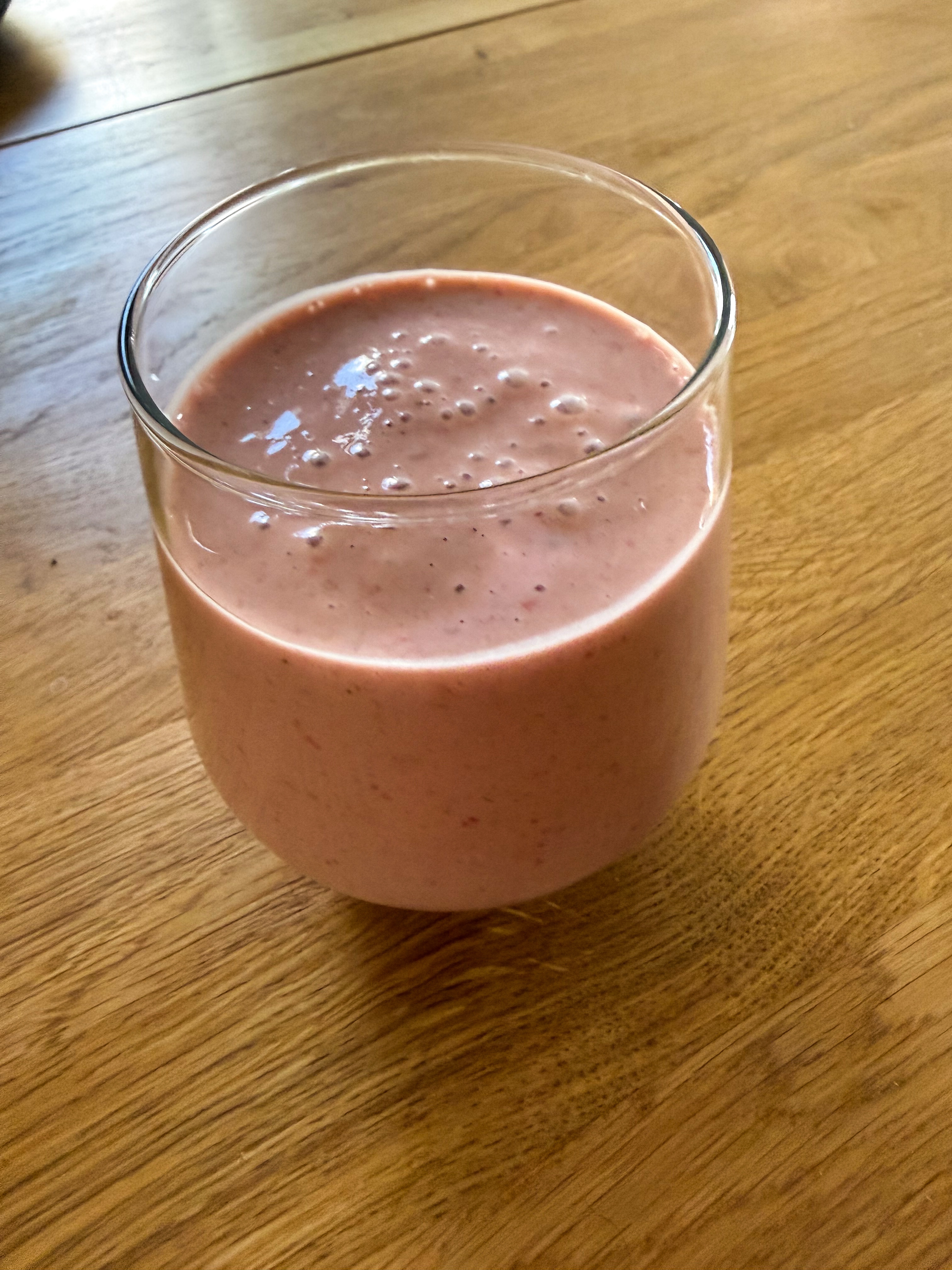 Breakfast smoothie on 2026-07-22: pink strawberry-raspberry smoothie in a glass on a wooden table
