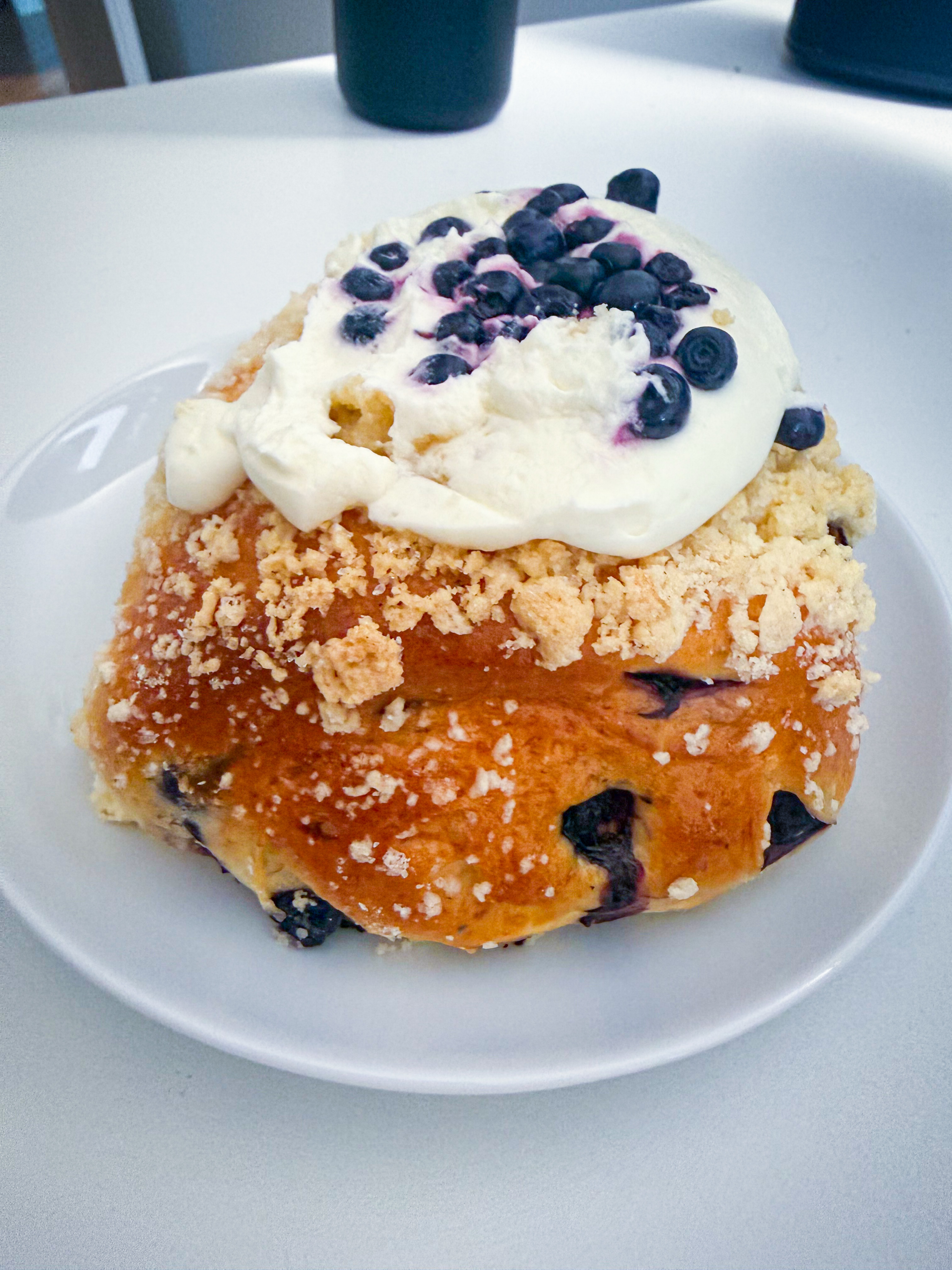 Sweet blueberry pastry on 2026-07-23 with crumb topping and a generous cream topping, served on a white plate