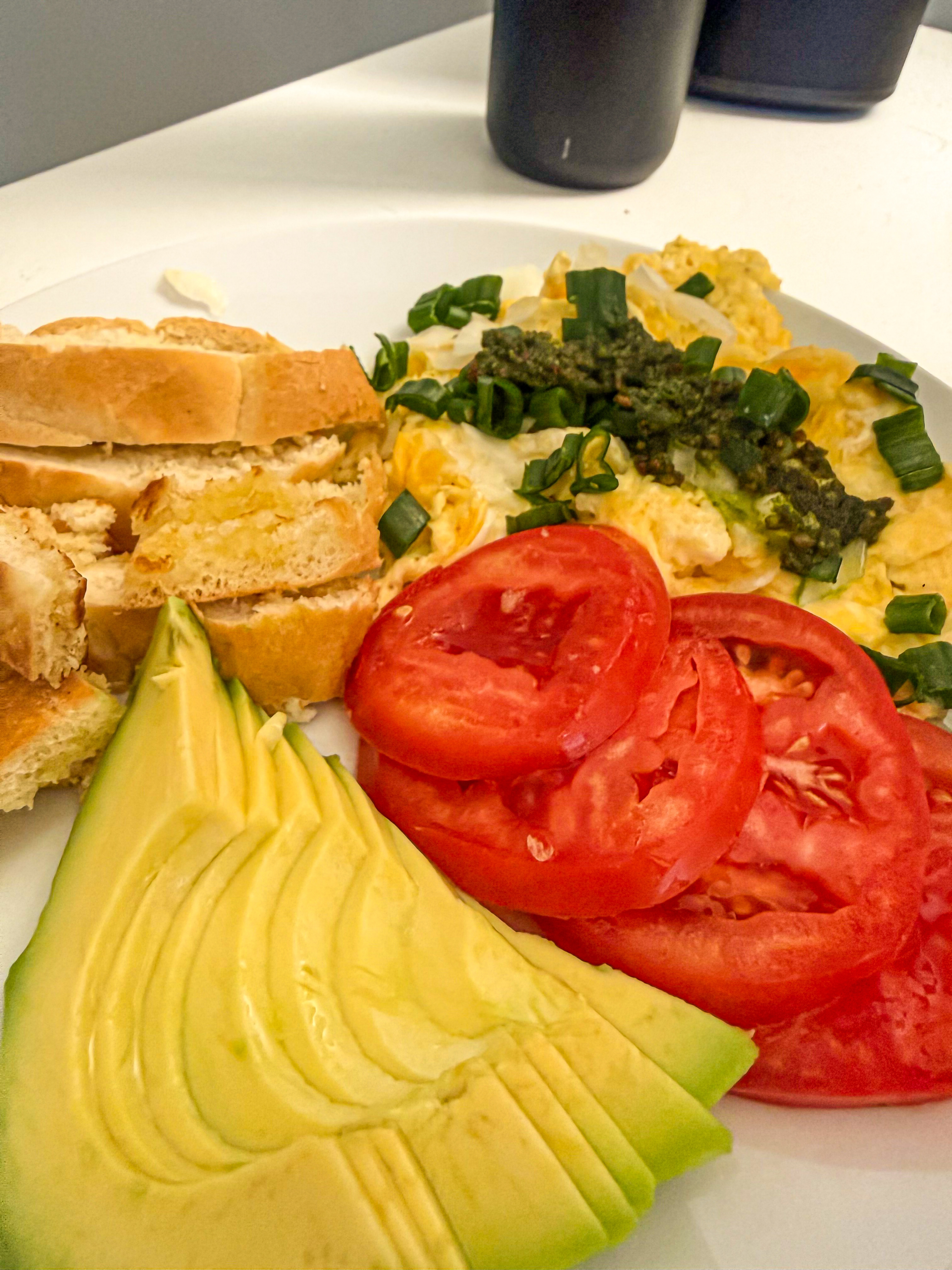 Breakfast on 2026-07-25: eggs with tomato, pesto, avocado, chives, and lemon juice, with bread visible on the plate