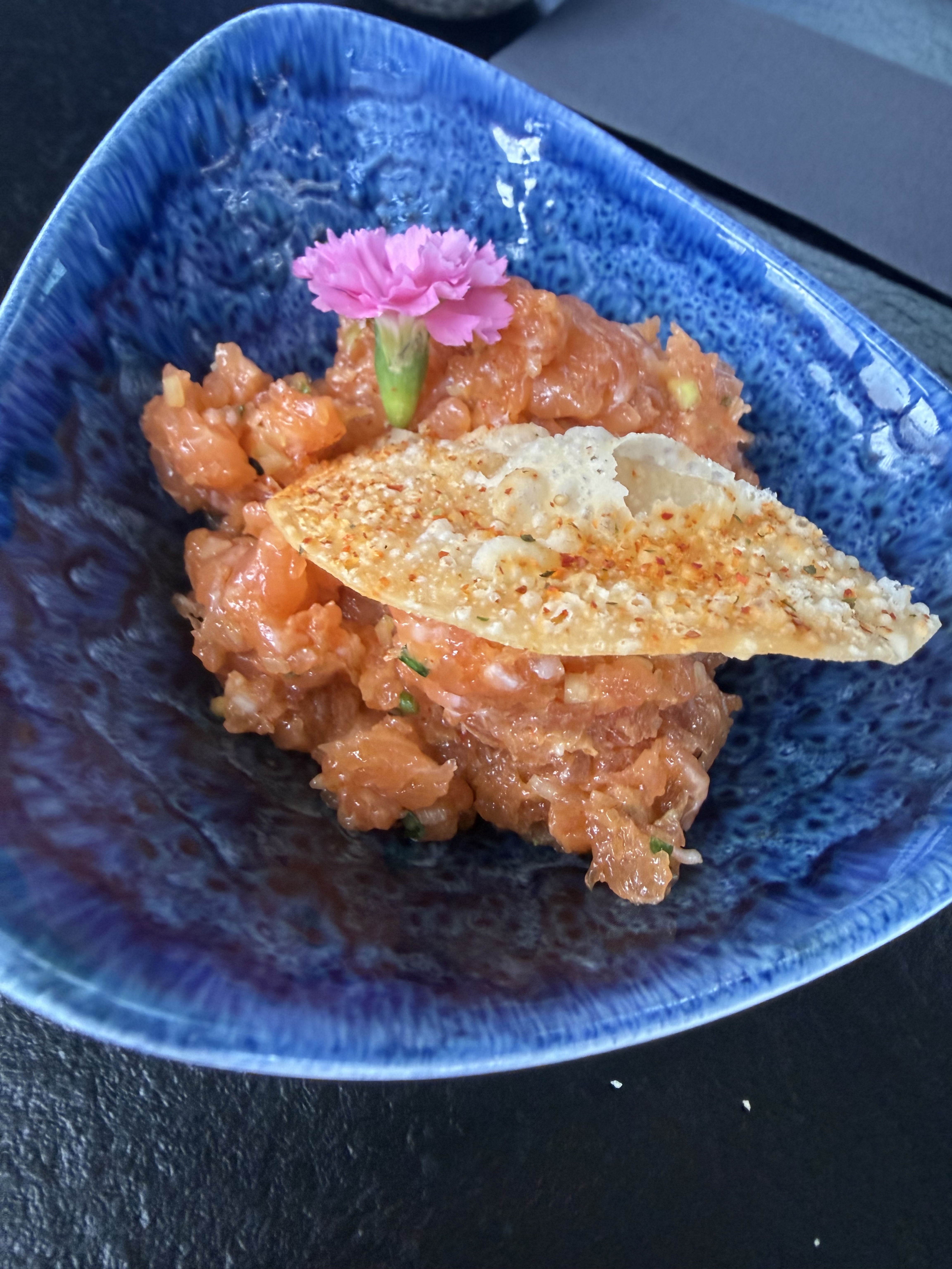 Dinner on 2026-07-28: chopped raw salmon or salmon tartare-style sushi plate in a blue bowl with a crisp garnish and edible flower